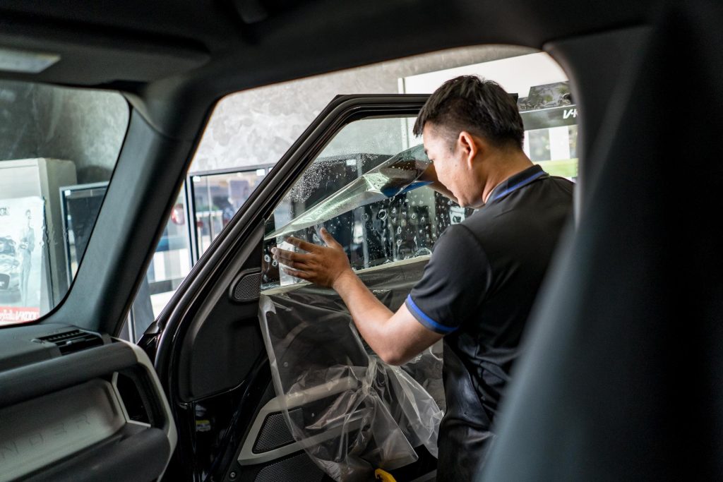 Worker washing glass windows of a car