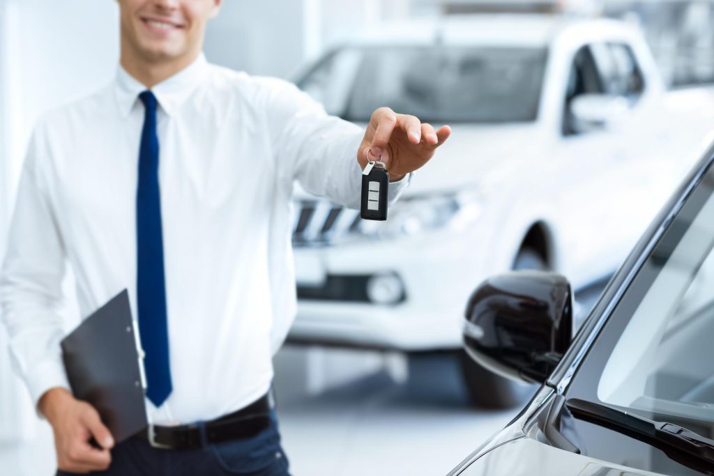 Professional holding a car key in the showroom to hand it to a client