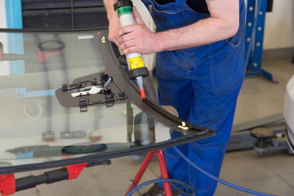 Worker applying silicone on car glass